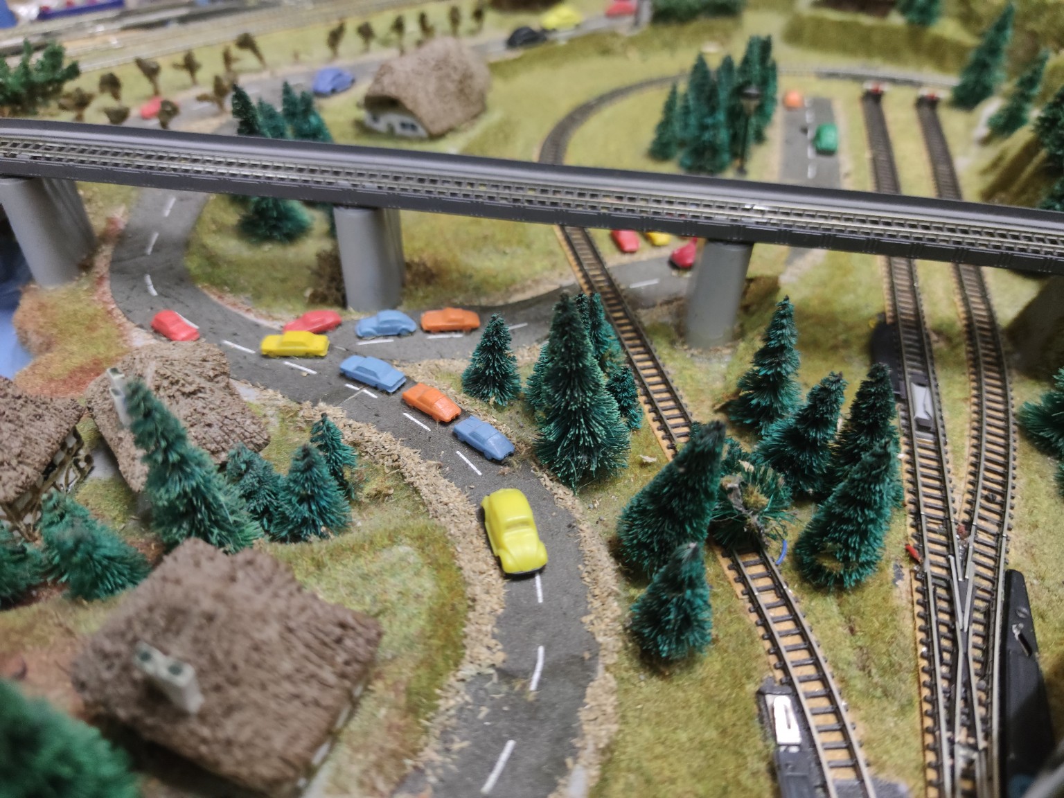 Ältere Modellbahnanlage mit Straßen und Fahrzeugen
