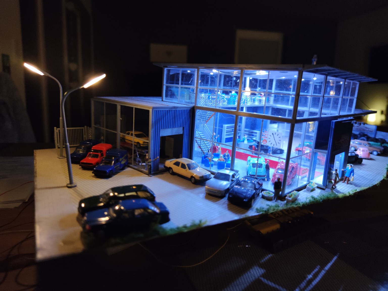 Beleuchtetes Autohaus mit Modellfahrzeugen und Figuren