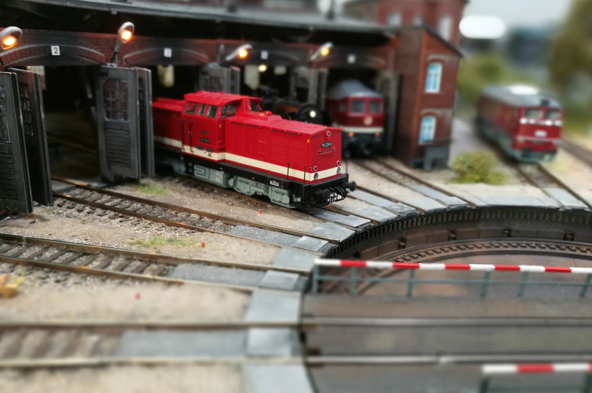 Modelleisenbahnlok vor einem Lokschuppen